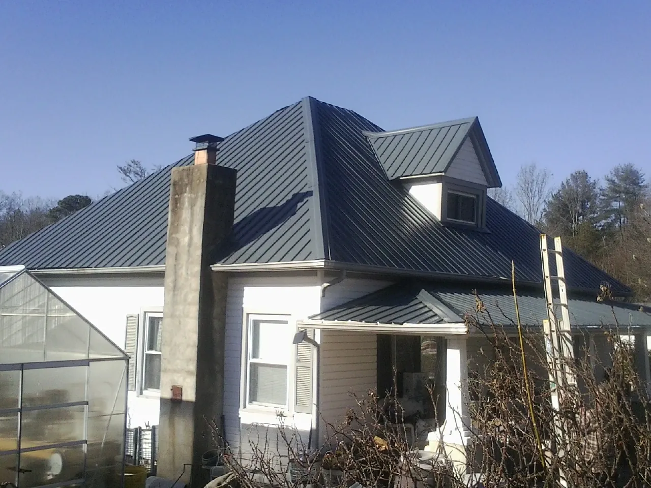 Dark blue standing seam metal roof on a white farmhouse with dormer — Slate & Tile Roof Repair by Roofing Brothers in Waukesha