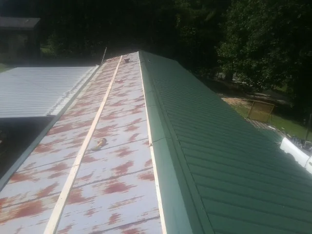 Old rusted panels beside newly installed green metal roofing — Wind Damage Roof Repair by Roofing Brothers in Waukesha