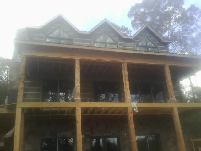 Dormers and porch framing on a large log home under construction — Roof Coating work by our crew in Waukesha