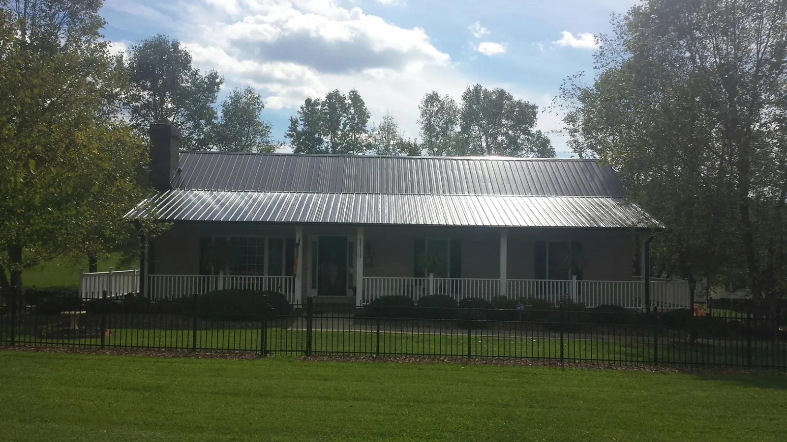 Gray metal roof on a brick ranch with a full width front porch — Gutter Guard Installation work by our crew in Waukesha