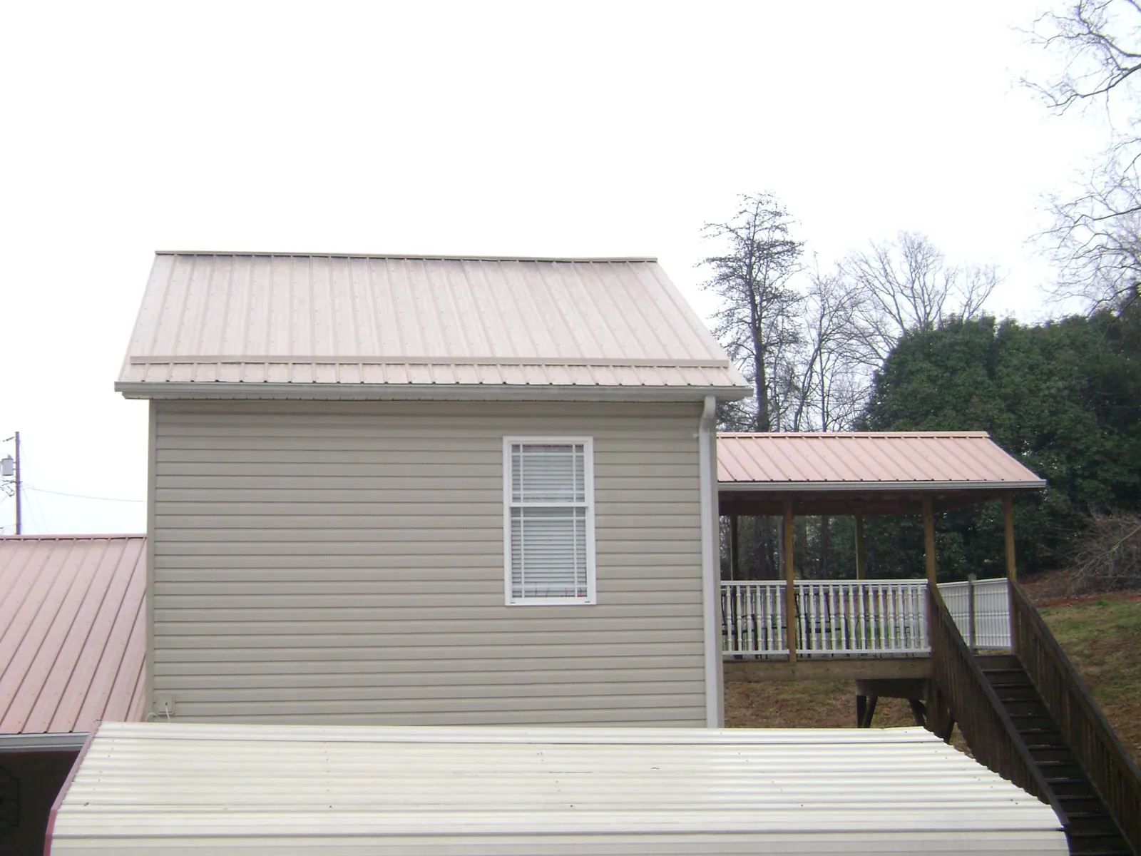 Tan metal roofs on a two story addition and attached porch, from a Roof Replacement job in Waukesha