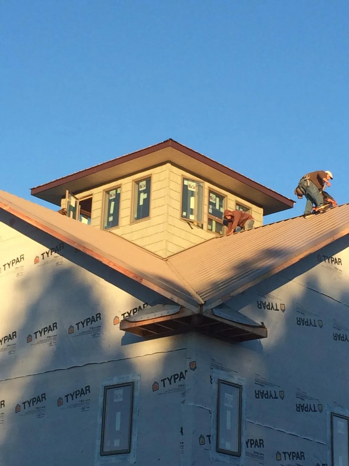 Roofers working around a rooftop cupola on a new metal roof at sunset — Roof Waterproofing in Waukesha by Roofing Brothers